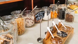 A buffet with various food items, including cereals, spreads, and bread.