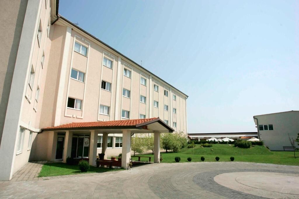 A multi-story building with a covered entrance and a landscaped courtyard.
