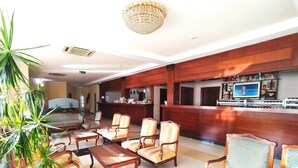 A lobby with wooden furniture, a reception desk, and a chandelier.