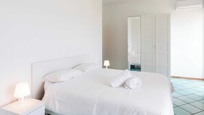 Une chambre d’hôtel avec un lit bien fait, une lampe de chevet, une armoire et un appareil de climatisation.