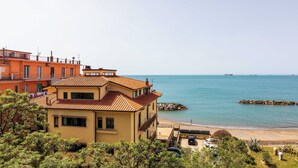 Un bâtiment situé sur la côte, doté d’un toit en tuiles, qui offre une vue sur une plage et la mer.
