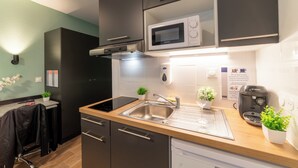 Una cocina moderna con un lavamanos de acero inoxidable, un microondas, una cafetera Bosch y una pequeña planta en maceta.