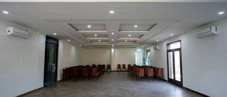 A conference room with rows of chairs, a wooden floor, and recessed lighting.