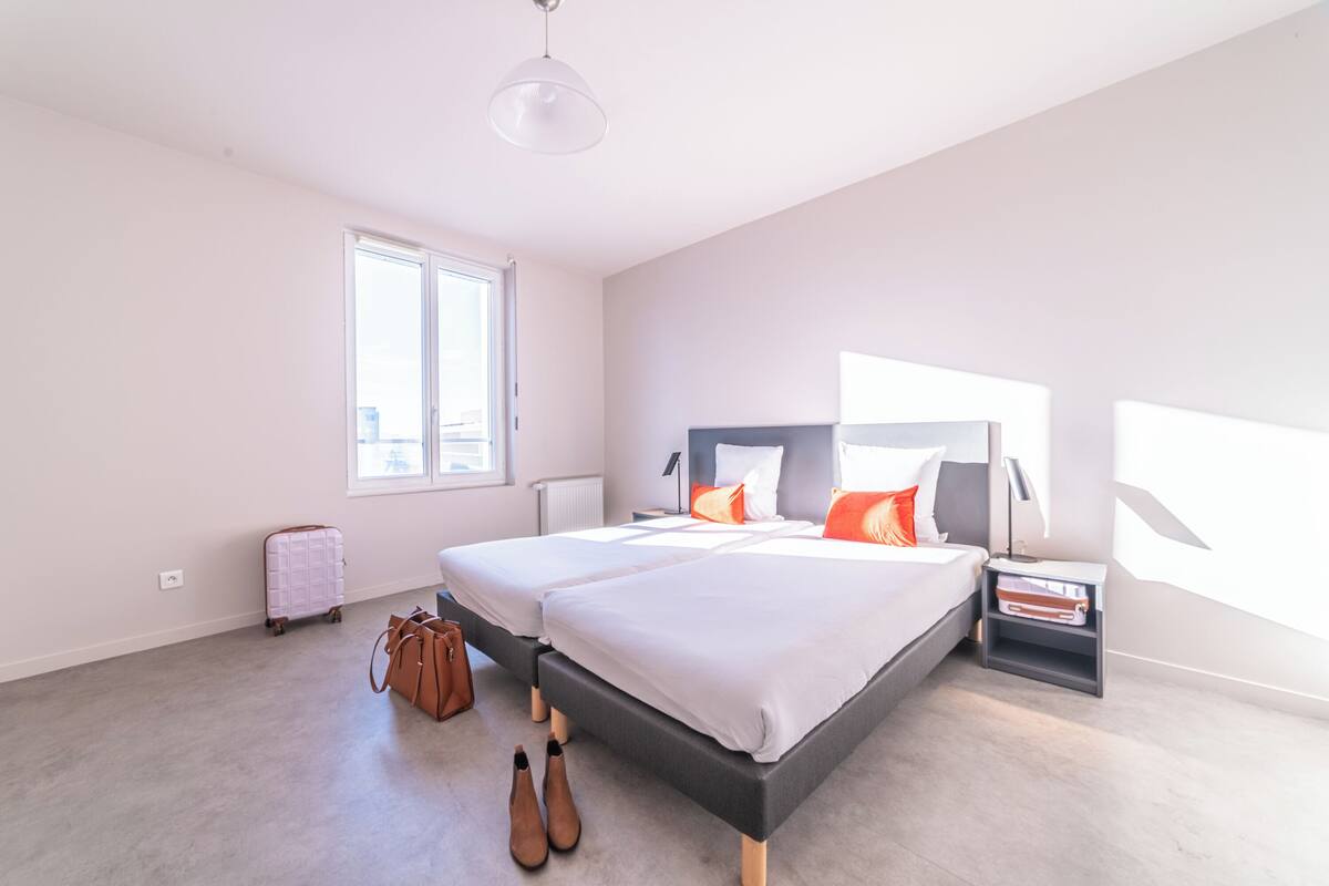 A modern bedroom with a large bed, a suitcase, and a pair of shoes on the floor.