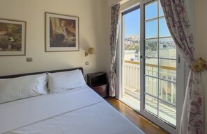 A hotel room with a large bed, a nightstand, a lamp, and two framed artworks on the wall. - The Observatory 2BR With Acropolis View (Athens)