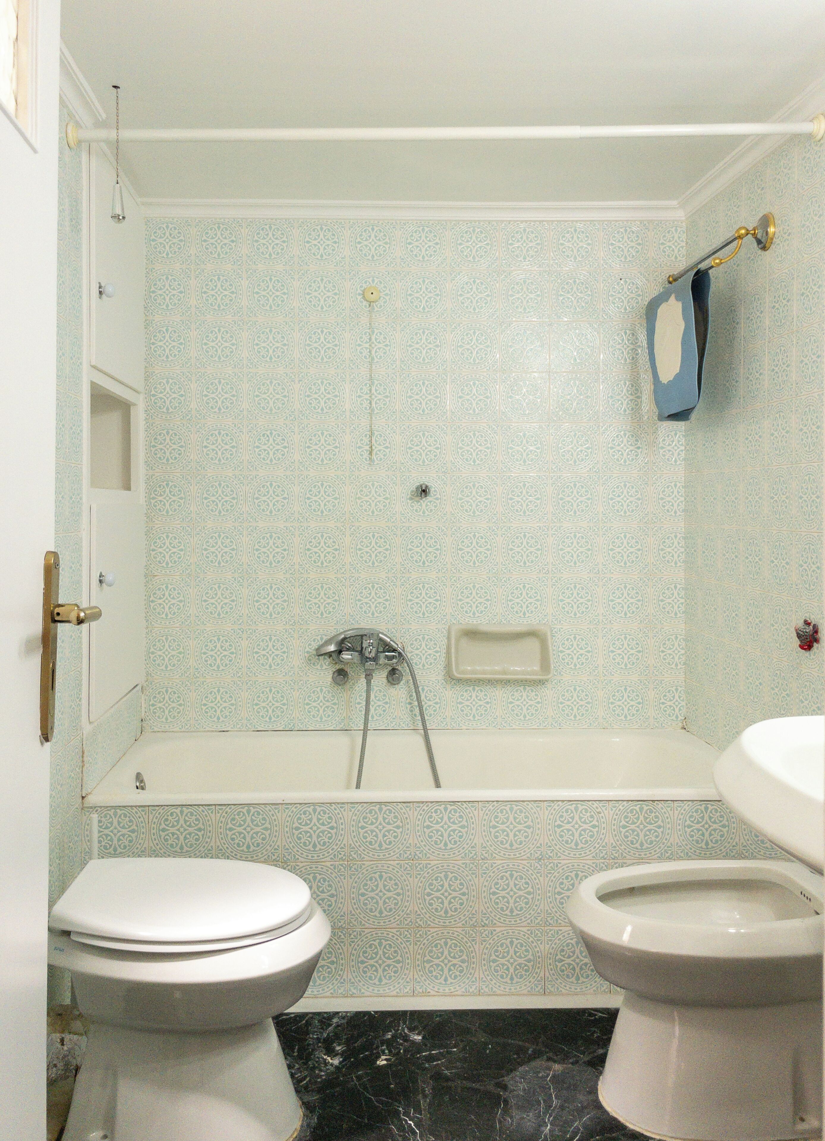 A bathroom with a bathtub, two toilets, and a shower.