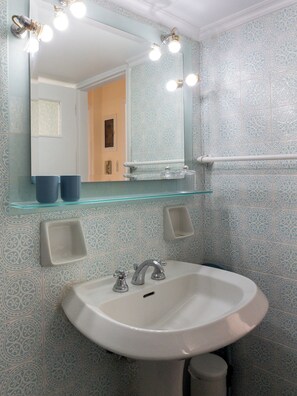 A bathroom with a white sink, a mirror with lights, and patterned tiles. - The Observatory 2BR With Acropolis View (Athens)