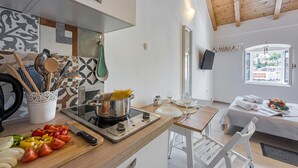 Une cuisine moderne équipée d’une cuisinière, d’une planche à découper et d’ustensiles de cuisine. On aperçoit également un coin repas avec une table et des chaises.