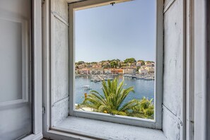 A window view of a coastal town with buildings and boats.