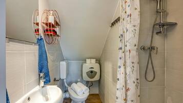 A small bathroom with a sink, toilet, shower, and a towel rack.