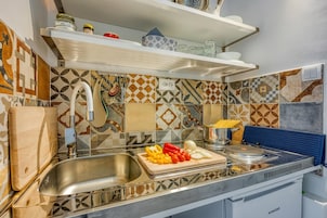 A kitchen with a sink, cutting board with vegetables, and a stove.