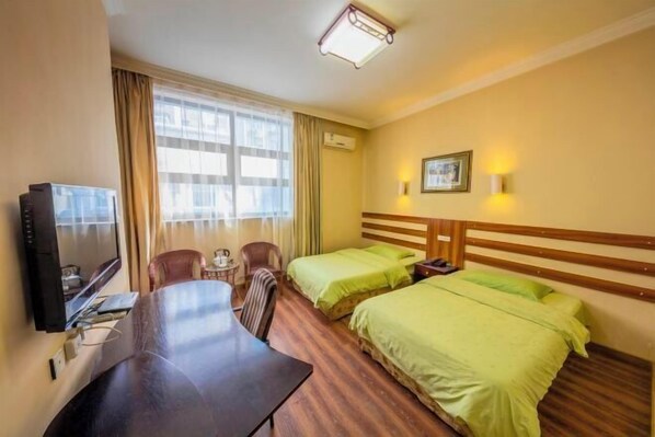 Ein Hotelzimmer mit Bett, Schreibtisch, Stuhl, Fernseher und Fenster.