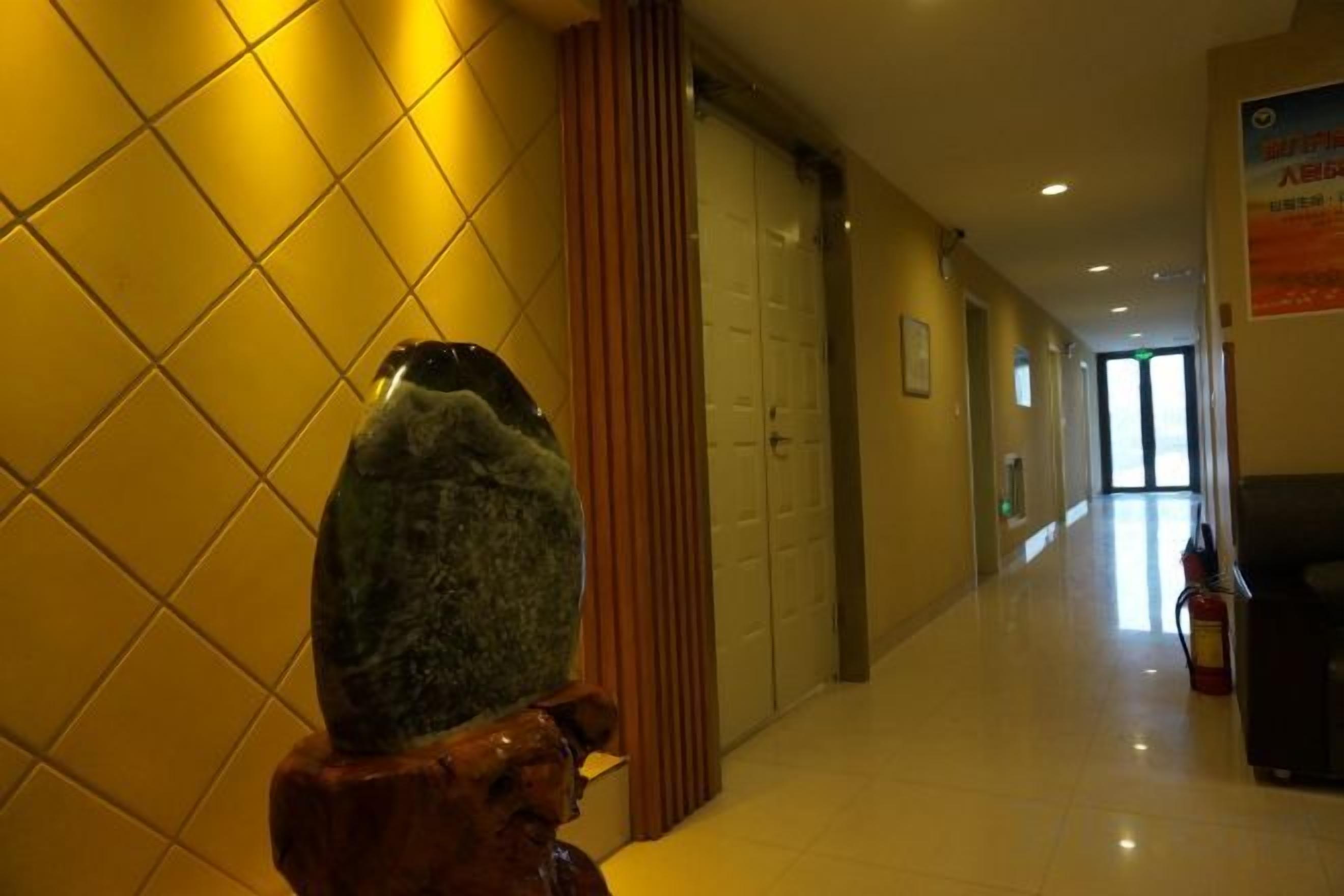 A hallway with a stone sculpture, wooden paneling, and a fire extinguisher.