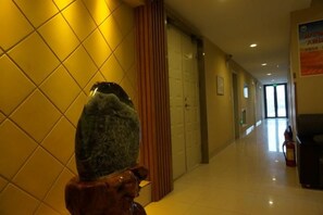 A hallway with a stone sculpture, wooden paneling, and a fire extinguisher. - Changji Express Hotel (Liaoyang)
