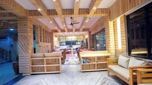 Een modern interieur met houten lambrisering, een centrale zithoek en een zichtbare keuken op de achtergrond.