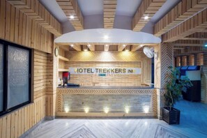 Aula, jossa on puusisustus, vastaanottotiski ja kyltti, jossa lukee: ”HOTEL TREKKERS INI”.