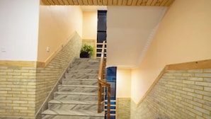 Een trap met een houten leuning, bakstenen muren en een uitzicht op een kamer aan de bovenkant.