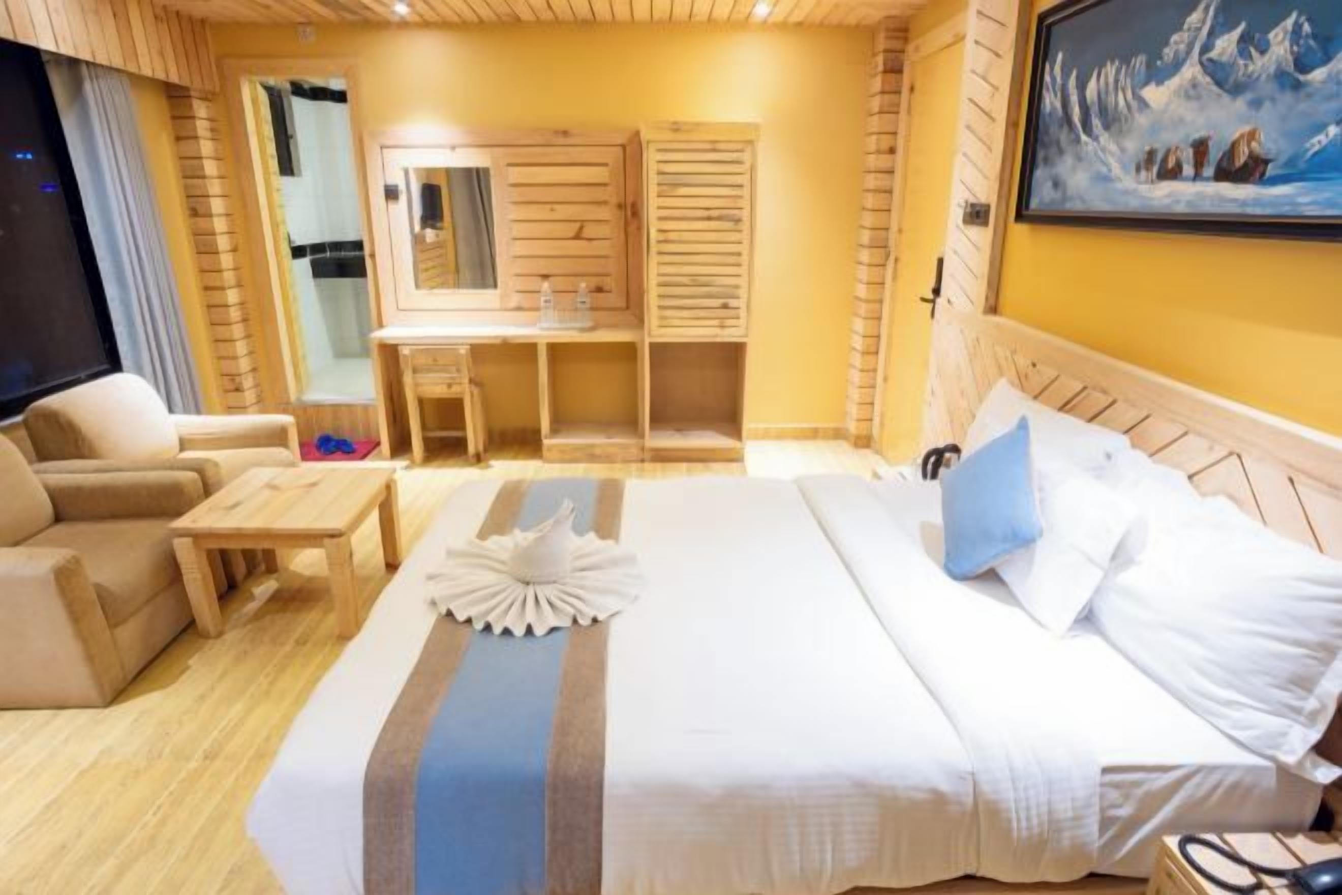 A hotel room with a bed, a desk, a chair, and a TV.