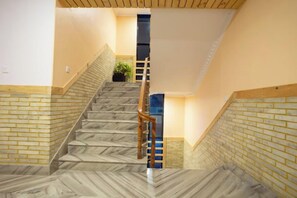 A staircase with a wooden handrail and a brick wall on one side.