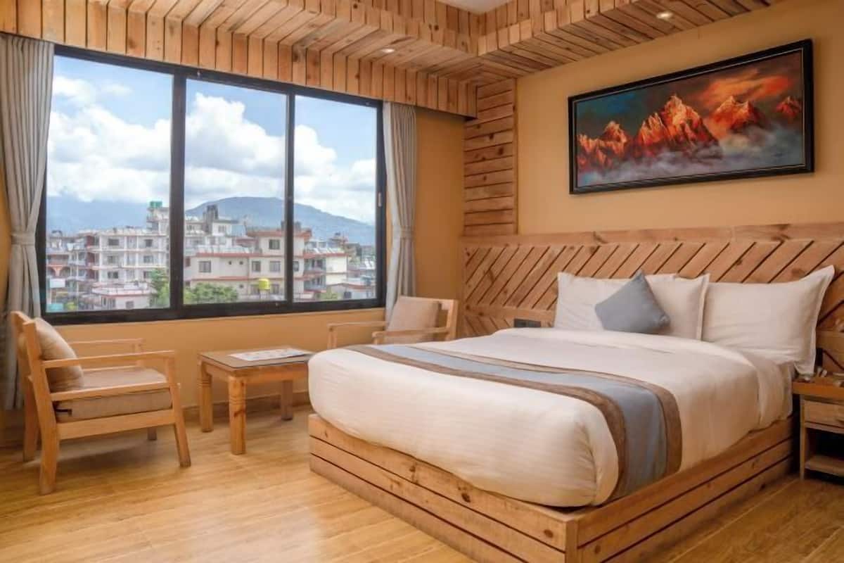 Een houten bed met uitzicht op gebouwen door een groot raam, een schilderij aan de muur en een houten vloer.
