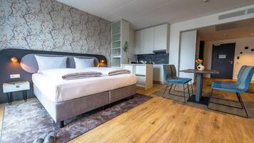 Ein modernes Hotelzimmer mit Bett, Nachttisch und einer kleinen Schreibtischzeile.