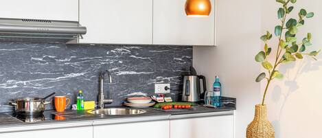 A modern kitchen with a marble backsplash, stainless steel appliances, and a decorative plant.