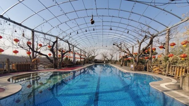 A swimming pool with a glass ceiling and trees with red lanterns. - Fuquan Xingong Hot Spring Resort (Zunhua)