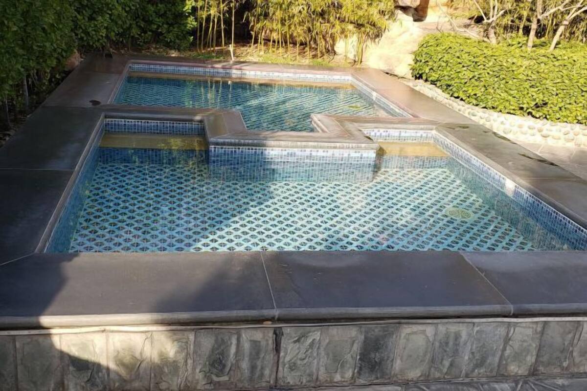 Une piscine rectangulaire dont le fond est recouvert de carreaux, entourée d’une bordure en pierre.