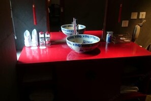 Ein roter Tisch mit einer Schüssel, einer Flasche und einem Behälter.