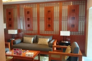 Ein Wohnzimmer mit einer Couch, Sesseln, einem Couchtisch und einer traditionellen Holzwand mit Fenstern.
