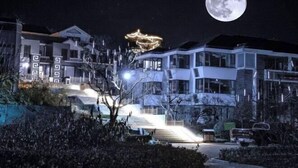 A modern residential building with a prominent staircase leading to the entrance, a large moon in the sky, and a decorative light fixture above the entrance. - Fuquan Xingong Hot Spring Resort (Zunhua)