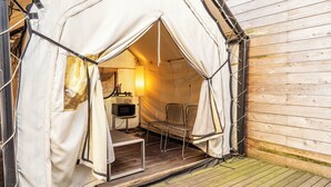 Un espace extérieur aménagé avec une tente, une table et des chaises, une lampe et un petit radiateur.