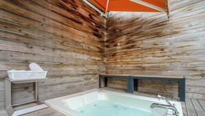 Une cabane en bois avec une baignoire, une petite étagère et un banc.