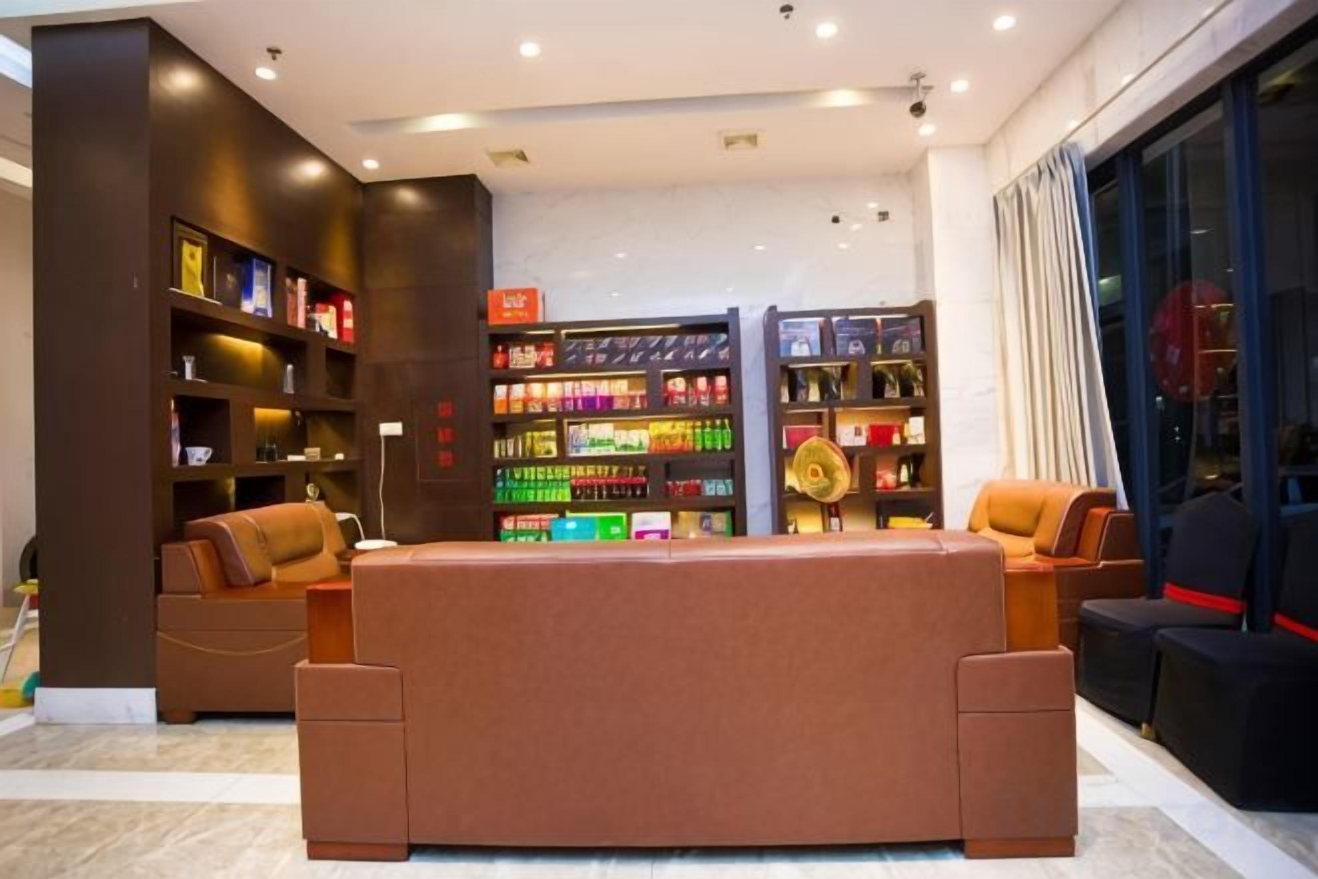 Een moderne hotel lobby met een centraal zithoek, een grote boekenkast en uitzicht op de stad.