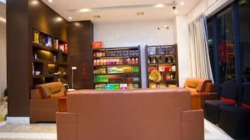 Een moderne hotel lobby met een centraal zithoek, een grote boekenkast en uitzicht op de stad.
