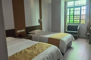 A hotel room with two beds, a nightstand, a chair, and a window with bars. - Nanuo Holiday Hotel (Sanya)