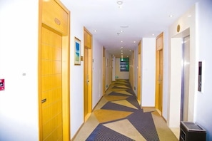 A hotel hallway with wooden doors, a patterned carpet, and an elevator.
