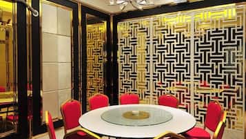 A dining area with a round table, red chairs, and a patterned wall.