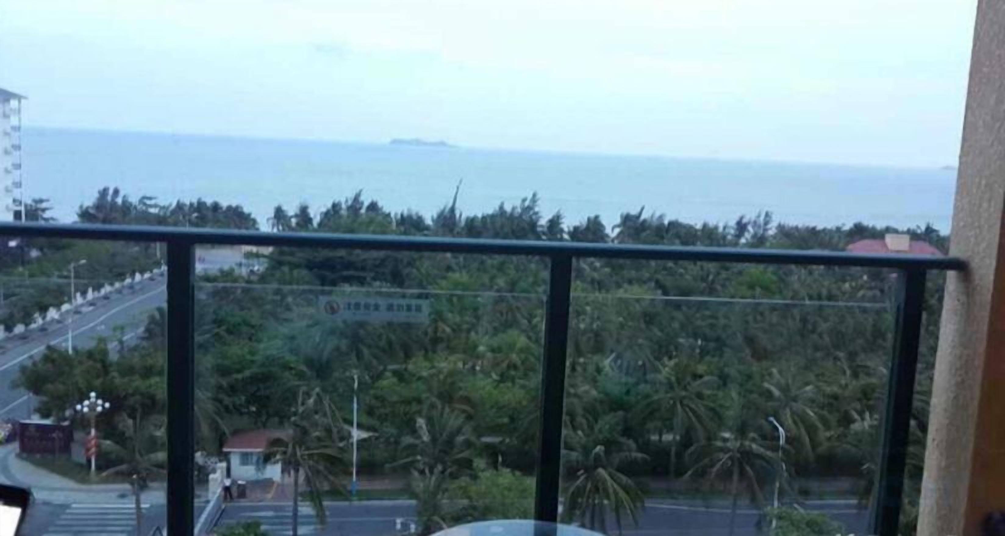 A balcony with a view of the sea and palm trees.