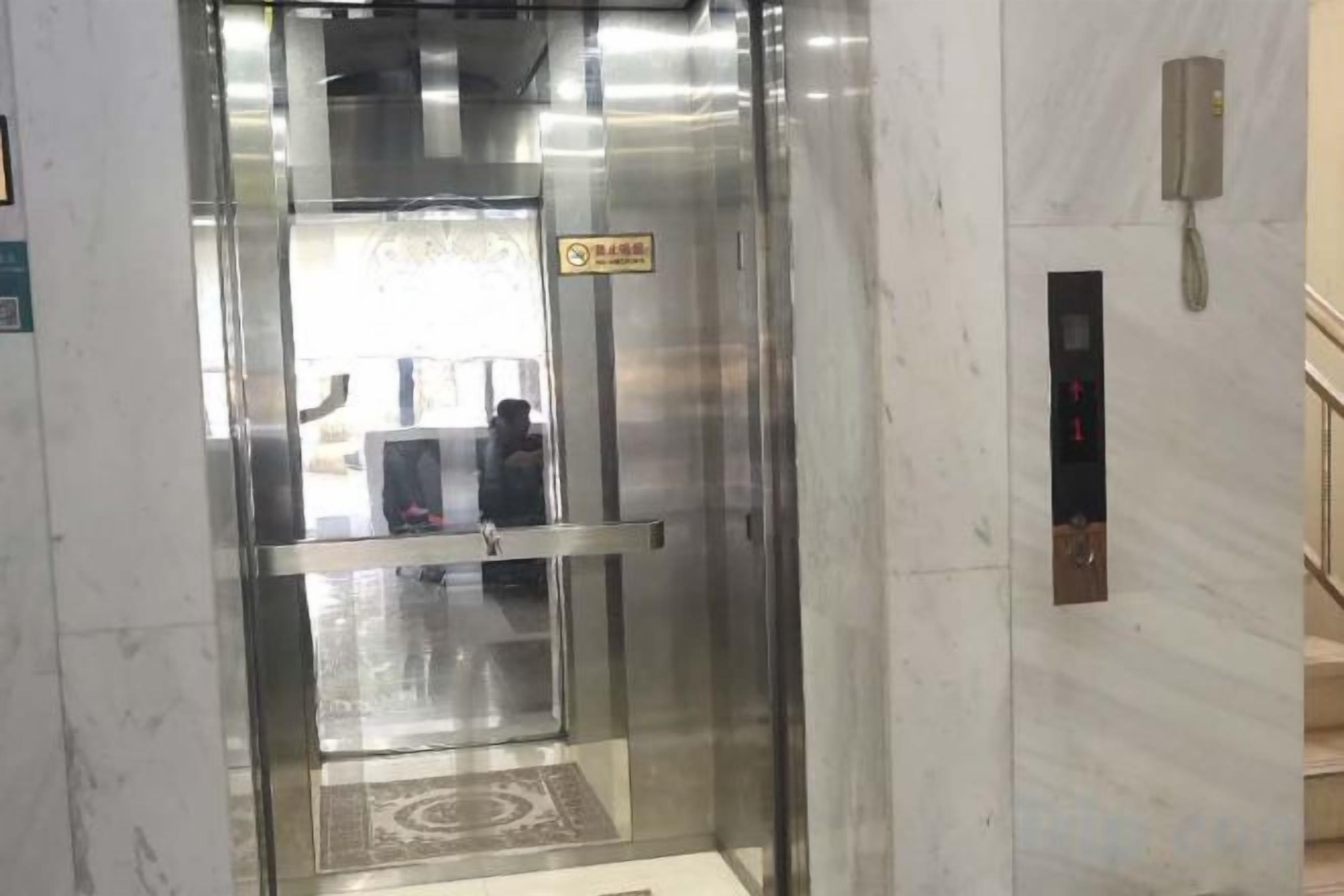 An elevator with a glass door, a phone, and a control panel with buttons.