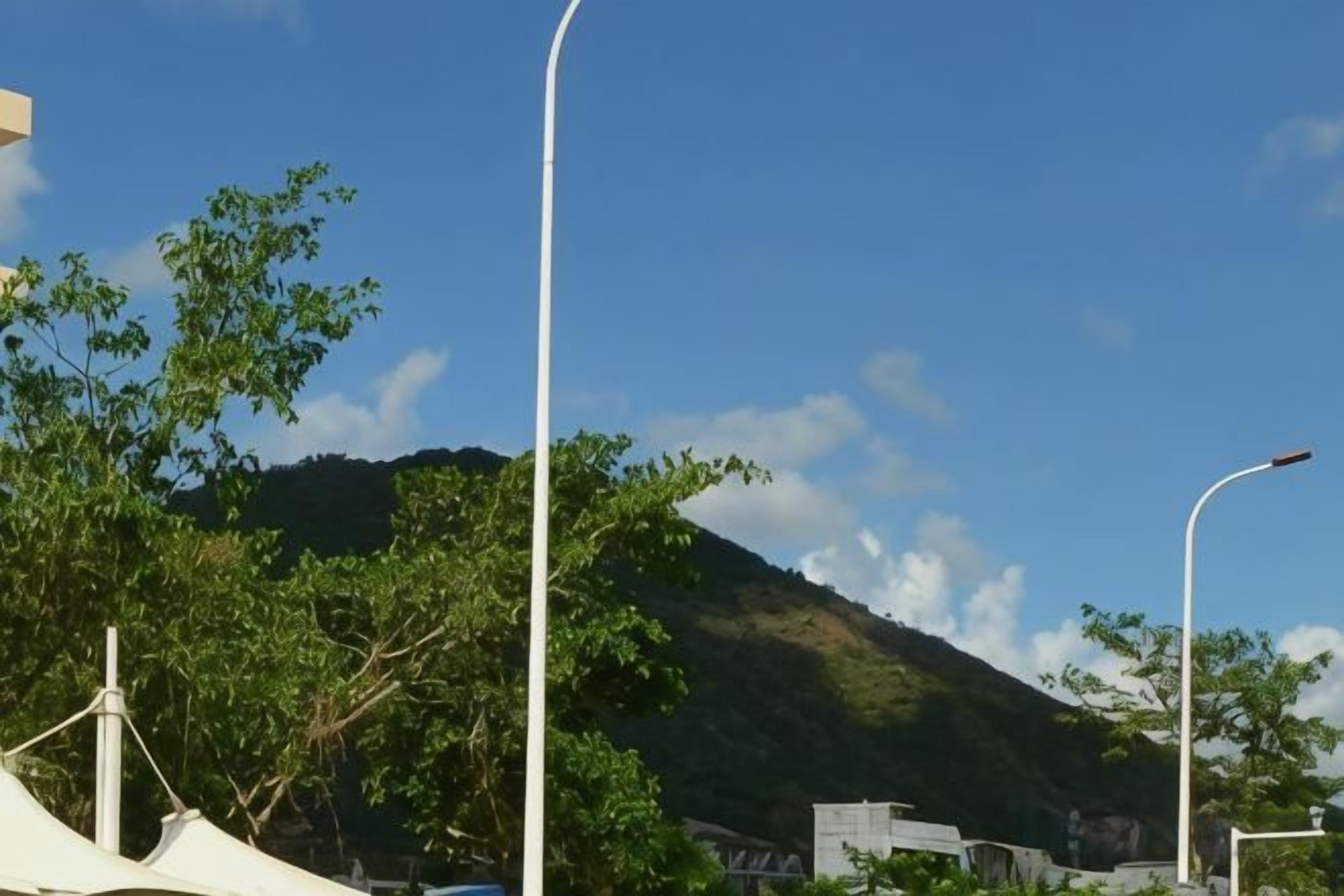 Eine Straße mit Bergen im Hintergrund, Straßenlaternen und Bäumen.