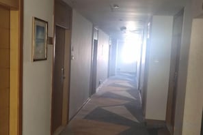 A hotel corridor with doors on both sides, a patterned carpet, and a light source at the end. - Nanuo Holiday Hotel (Sanya)