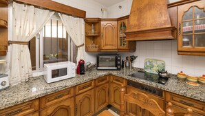 A kitchen with wooden cabinets, a microwave, a toaster, and a stove. - Enjoy Arcos in Arcos de la Frontera (Arcos de la Frontera)