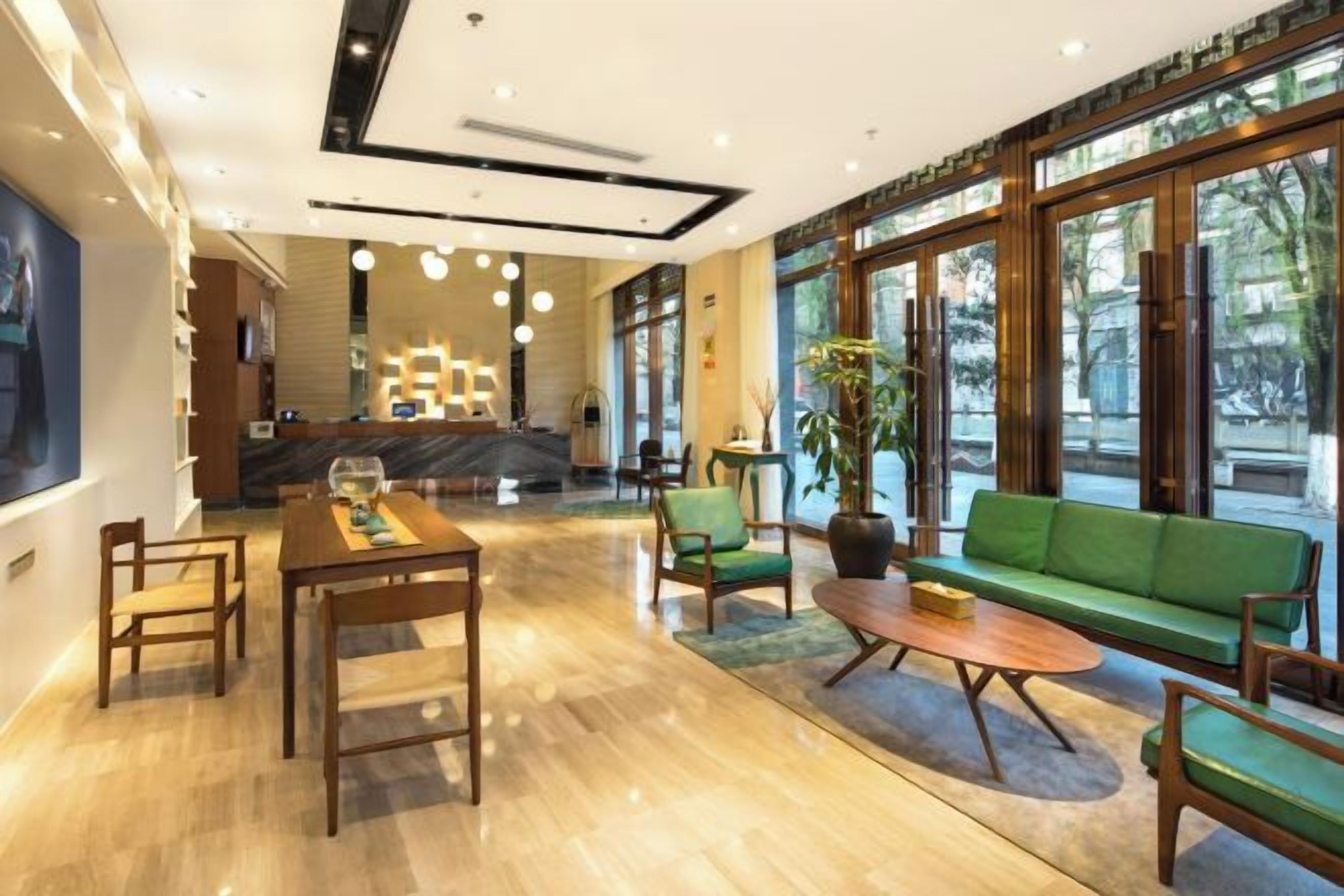 A hotel lobby with a reception desk, seating area, and large windows.