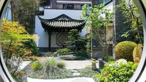 A traditional Chinese architectural structure with a tiled roof, surrounded by lush greenery and a stone pathway. - Starway Hotel (Dujiangyan Scenic Area Nanqiao) (Dujiangyan)