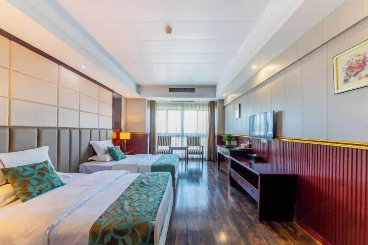 Une chambre d’hôtel avec deux lits, une télévision, un bureau et une fenêtre donnant sur un paysage agréable.