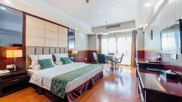 A hotel room with a large bed, a desk, a chair, a TV, and a window.