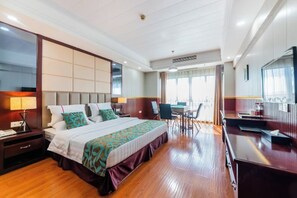 Una habitación de hotel con una cama grande, un escritorio, una silla, un televisor y una ventana.