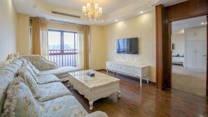 Una sala de estar con sofá, mesa de centro, televisor y balcón.