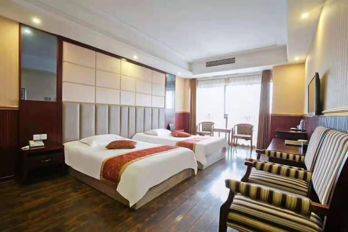 Une chambre d’hôtel avec deux lits, un canapé, une chaise, une petite table et un miroir.